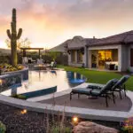 Custom backyard design with curved pool, rock retention wall and multiple seating areas.