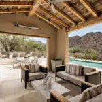 Custom backyard design with shade structure, multiple seating areas, outdoor fan and outdoor entertainment area.