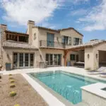 Custom backyard design with blue pool, raised spa and metal trellis.