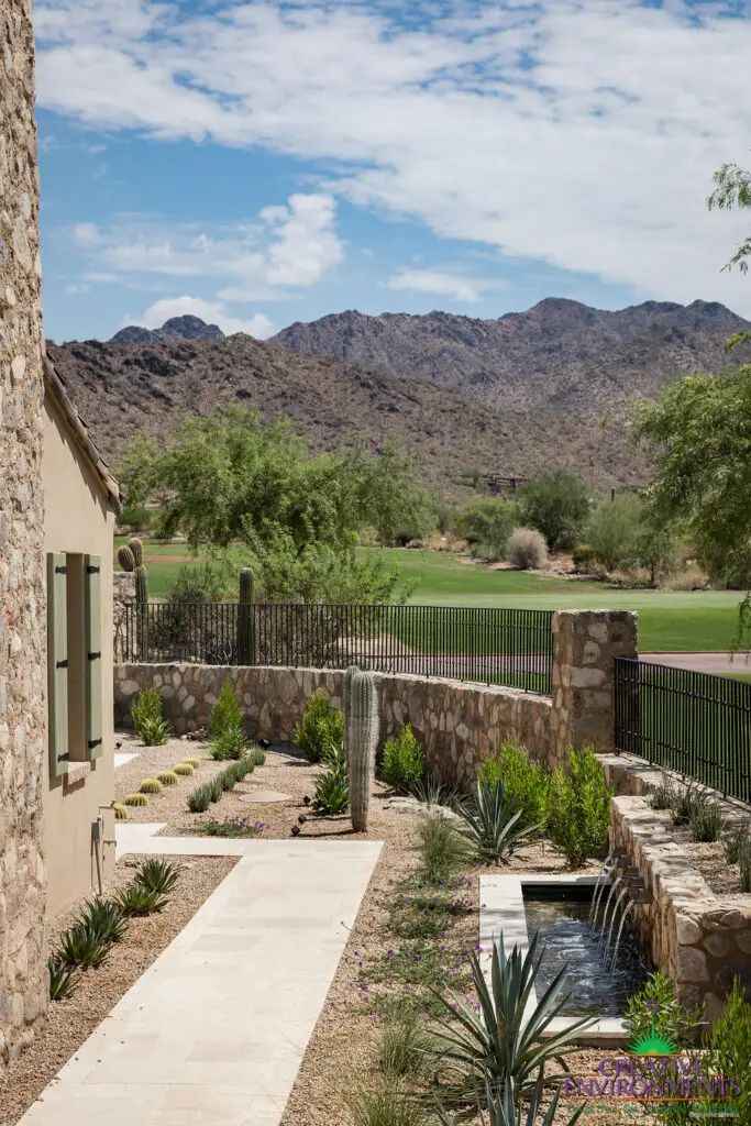 Custom backyard design with organized planting, natural stone accents and metal scupper water feature.