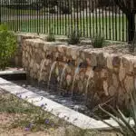 Custom backyard design with metal scupper water feature, natural stone accents and organized planting.