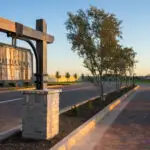 Custom community entrance with hanging sign, mixed material driveway and large water fountain.