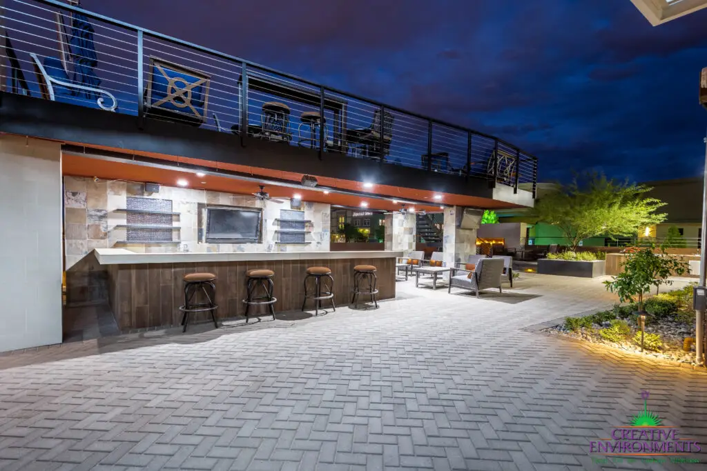Custom patio design with two-story shade structure, uplighting and fireplace.