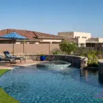 Custom backyard design with curved pool, raised spa and natural stone retention walls.