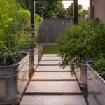 Custom backyard design with trellis archway, galvanized planters and natural stone steps.