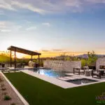 Custom backyard design with natural stone pool wall with metal water feature, Jesus steps and angled shade structure.