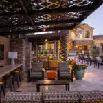 Custom community amenities with patterned metal shade structure, multiple seating areas and outdoor TVs.