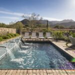 Custom backyard design with water scuppers into pool, multiple seating areas and brick deck.