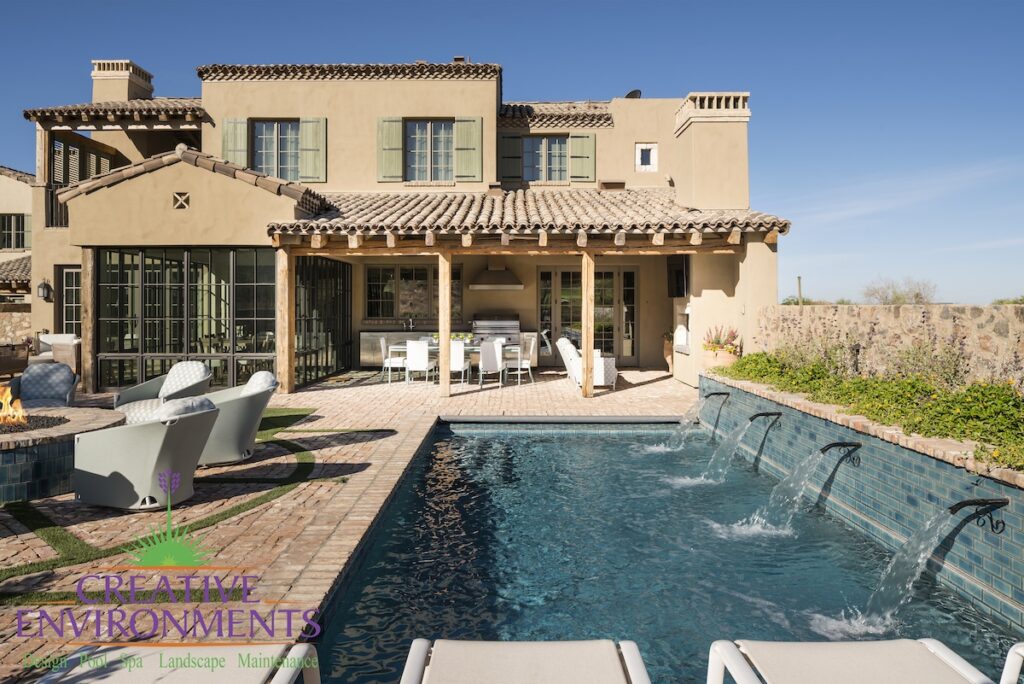 Custom backyard design with flowers, water scuppers into pool and patterned turf.