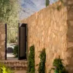 Custom side metal gate with greenery and metal fencing.