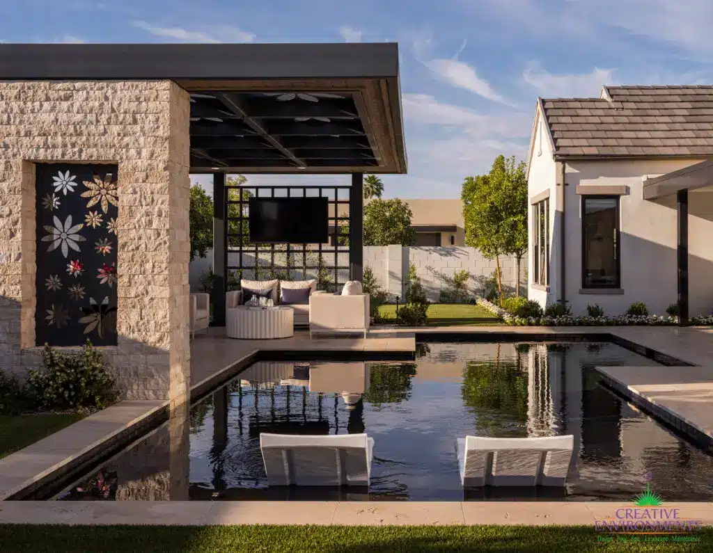 Custom shade structure with floral cutouts, natural stone columns and outdoor TV.