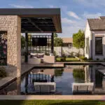 Custom shade structure with floral cutouts, natural stone columns and outdoor TV.