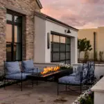 Custom front yard design with cantilevered fire table, annuals and natural stone privacy wall.