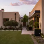 Custom backyard design with artificial turf, organized planting and large metal planters.