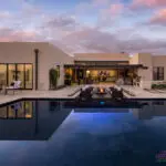 Custom backyard design with natural stone decking, large pool and multiple seating areas.