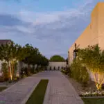 Custom side yard design with brick pavers, organized planting and up lighting.