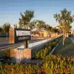 Custom community entrance with cantilevered metal entryway sign, organized planting and long water feature.