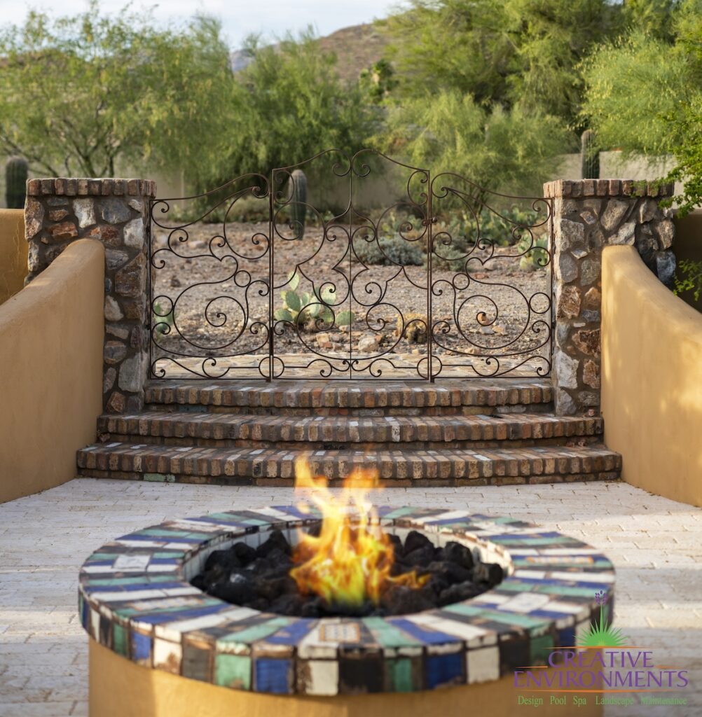 Backyard design with brick steps, fire pit and metal gate.