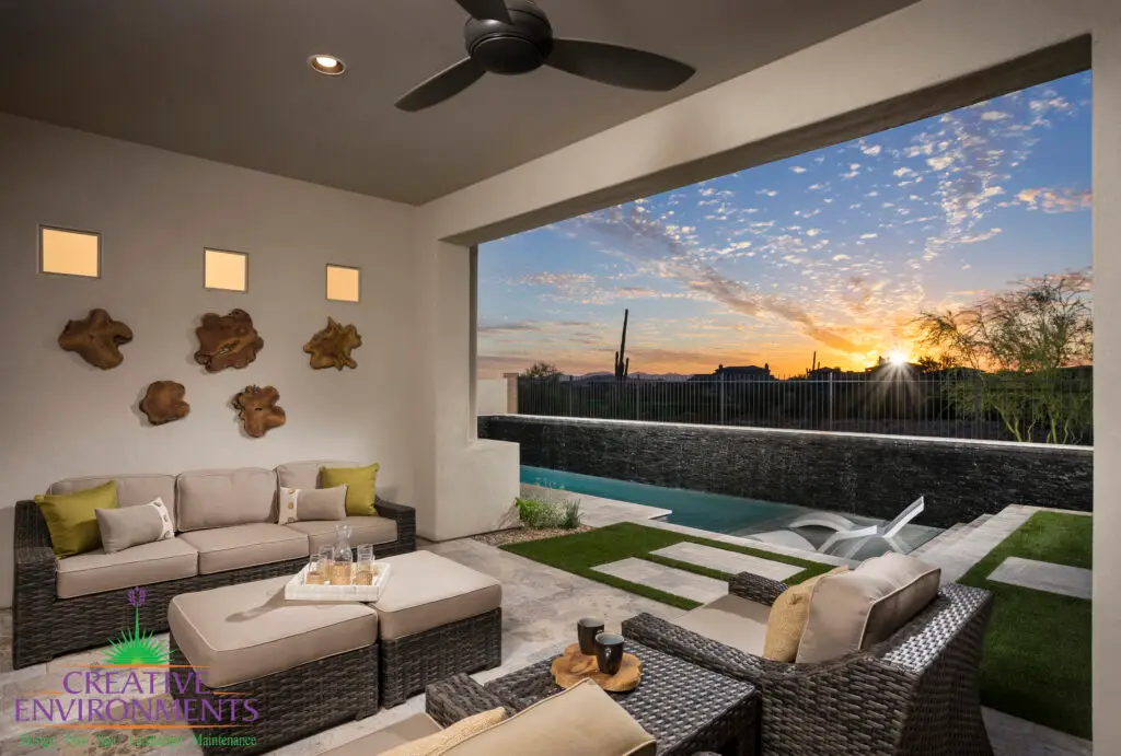 Custom backyard design with natural stone paver teps, black water wall feature and metal fencing.