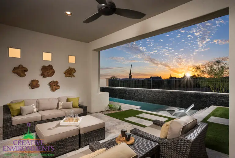 Custom backyard design with natural stone paver teps, black water wall feature and metal fencing.