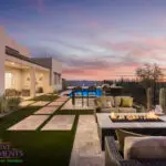 Custom backyard design with natural stone paver steps, multiple seating areas and blue pool.