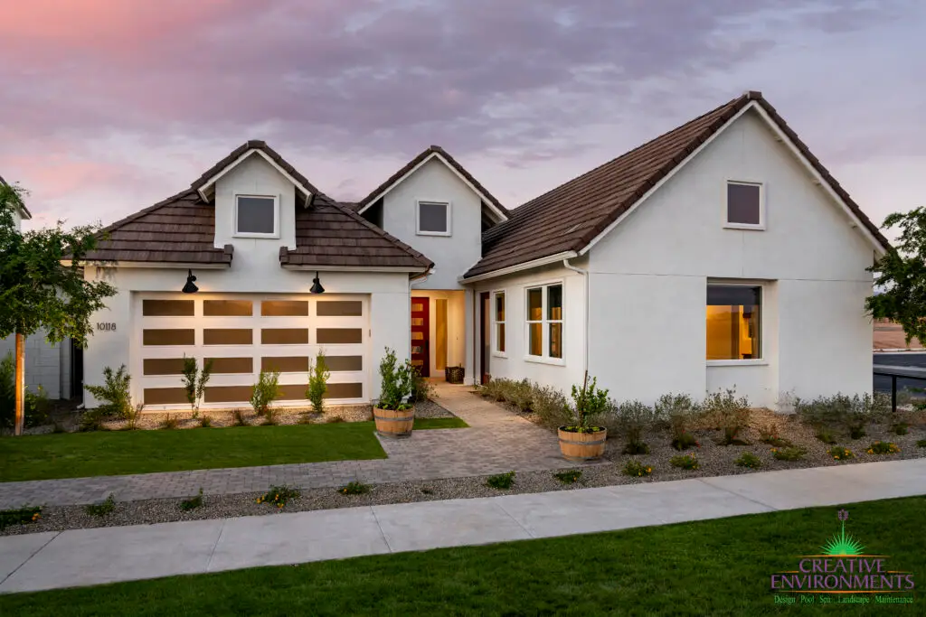 Custom front yard design with organized planting, brick paver walkway and large planters.