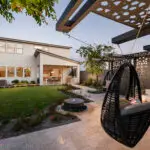 Custom backyard design with hanging swing, water feature and real grass.