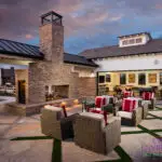 Custom community amenities with patterned turf, large fireplace with chimney and multiple outdoor seating areas.