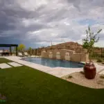 Custom backyard design with large planters, metal shade structure and metal fencing.