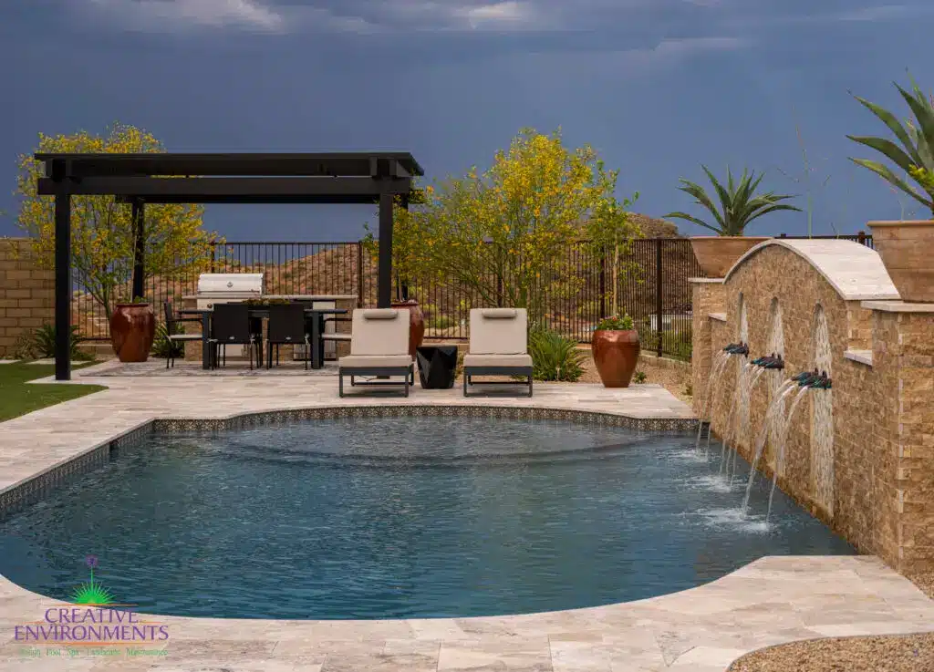 Custom backyard design with unique-shaped pool, metal scupper water feature into deco-tile pool and multiple seating areas.
