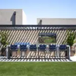 Custom backyard design with bar seating, outdoor TV and slatted metal shade structure.