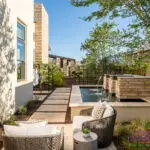 Custom backyard design with metal trellis, metal scupper water feature and natural stone paver steps.