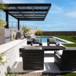 Custom backyard design with cantilevered shade structure, fire table with seating area and organized planting along the perimeter of the property.