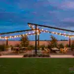 Backyard design with anged metal feature and string lights.