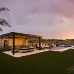 Custom backyard design with metal shade structure, multiple seating areas and pool.