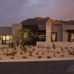 Custom front yard design with paver driveway, organized planting and natural stone privacy wall.