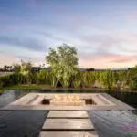 Custom backyard design with sunken fire pit into pool, Jesus steps and privacy hedges.