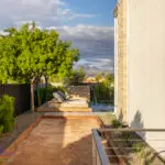 Custom side yard design with bocce ball court, water feature into pool and lounging area.