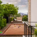 Custom backyard design with bocce ball court, privacy hedges and metal fencing.