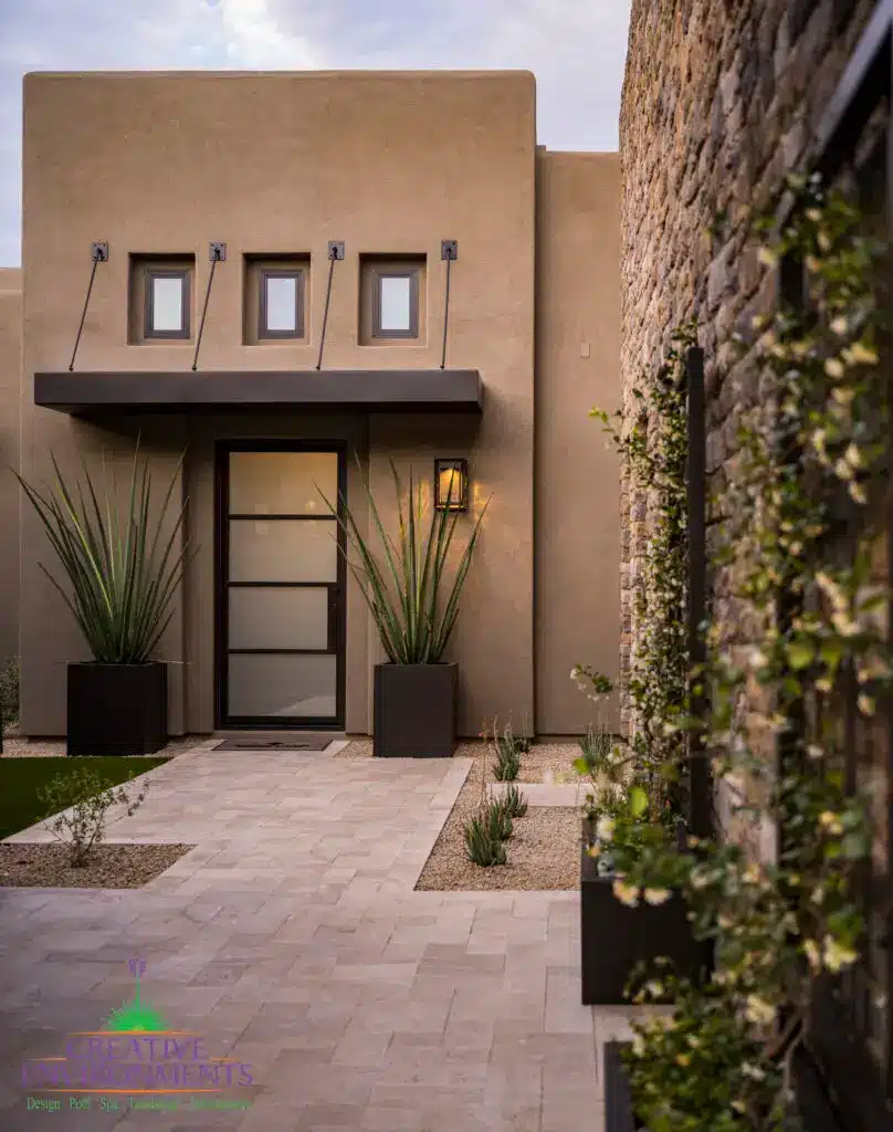Custom front yard design with large metal planters, metal trellis and natural stone pathway.