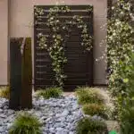 Custom backyard design with metal trellis, river rock and artificial turf.