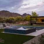 Custom backyard design with custom metal shade structure, blue spa and multiple seating areas.