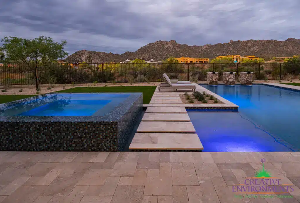 Custom backyard design blue raised spa, blue pool and water columns.