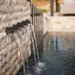 Custom metal scupper water feature into pool with slatted metal statement piece.