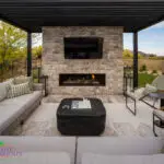 Custom backyard design with natural stone fireplace, metal fencing and outdoor seating area.