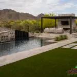 Custom backyard design with custom water feature into pool, artificial turf and natural stone decking.