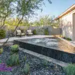 Custom backyard design with triangular spa, organized planting and privacy wall.