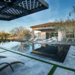 Custom backyard design with cantilevered shade structure, natural stone steps and large planters with trees and small succulents.