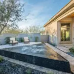 Custom backyard design with triangular spa, prviacy wall and raised outdoor seating area.