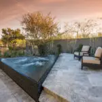 Custom backyard design with triangular spa, raised seating area and privacy wall.